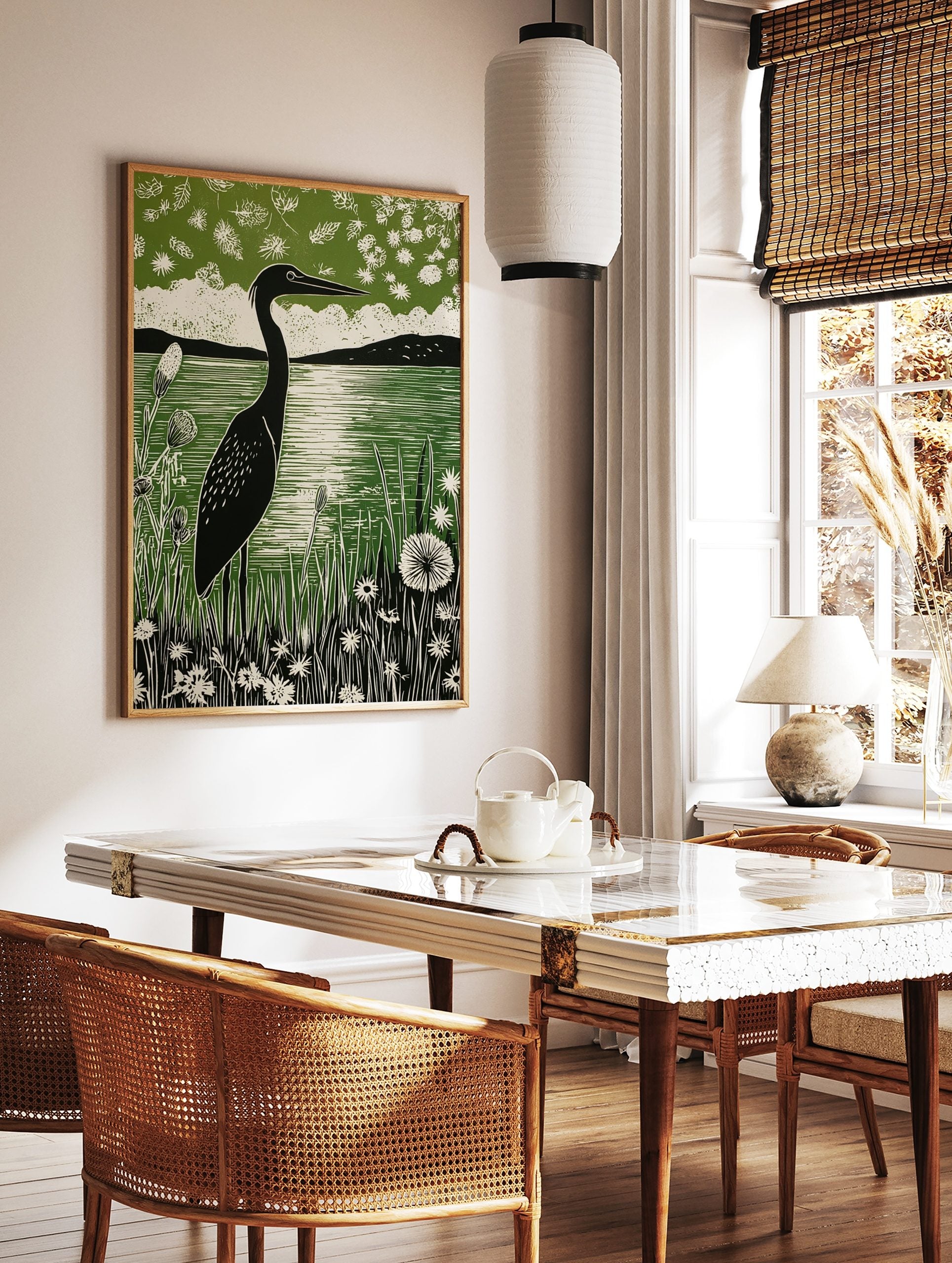 Linocut print of a black heron by a green lake, surrounded by white wildflowers and distant hills, in a styled room mockup