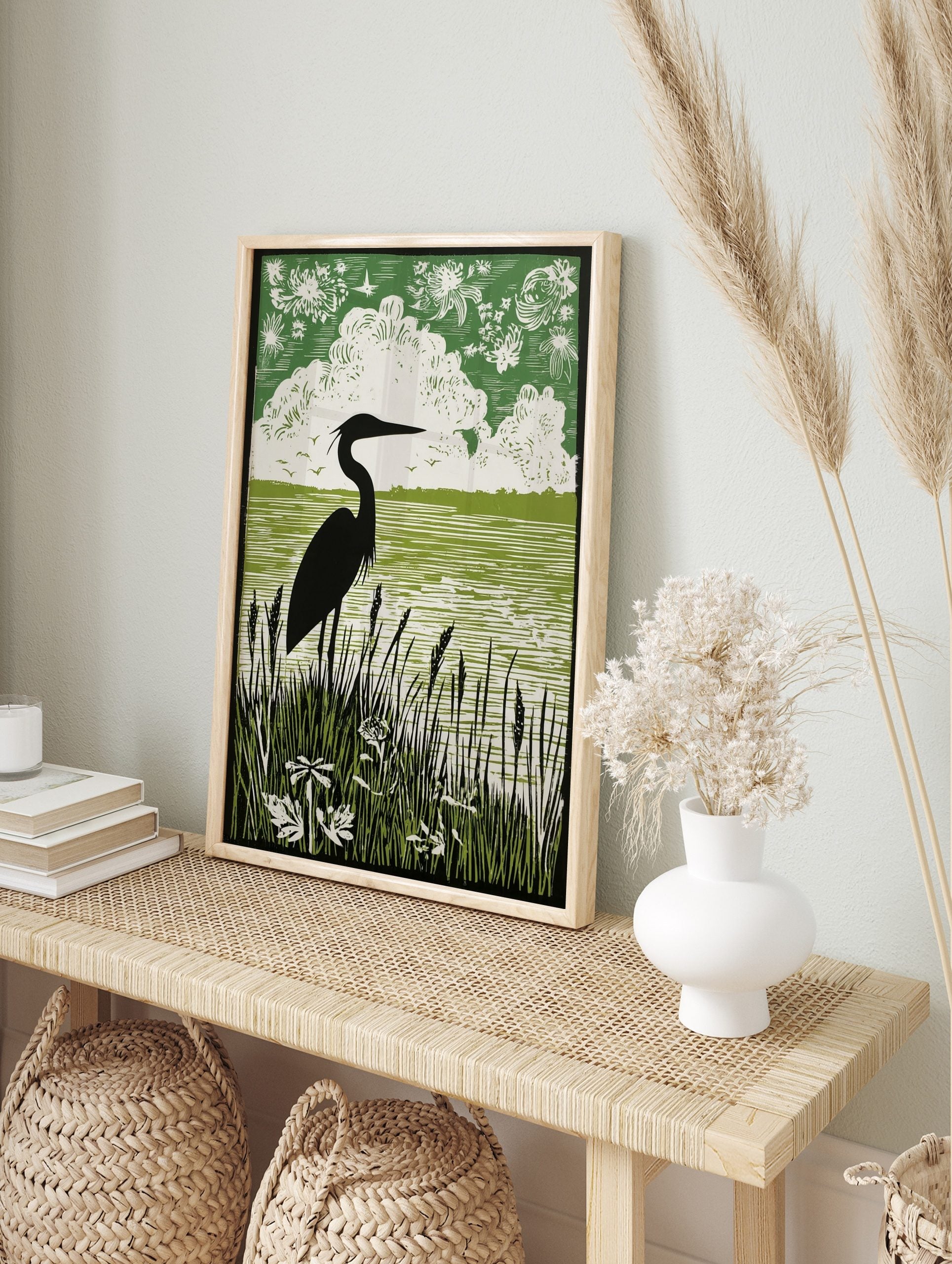Black heron silhouette art print with green water, white clouds, and dark reeds in linocut, in an alternate framed mockup