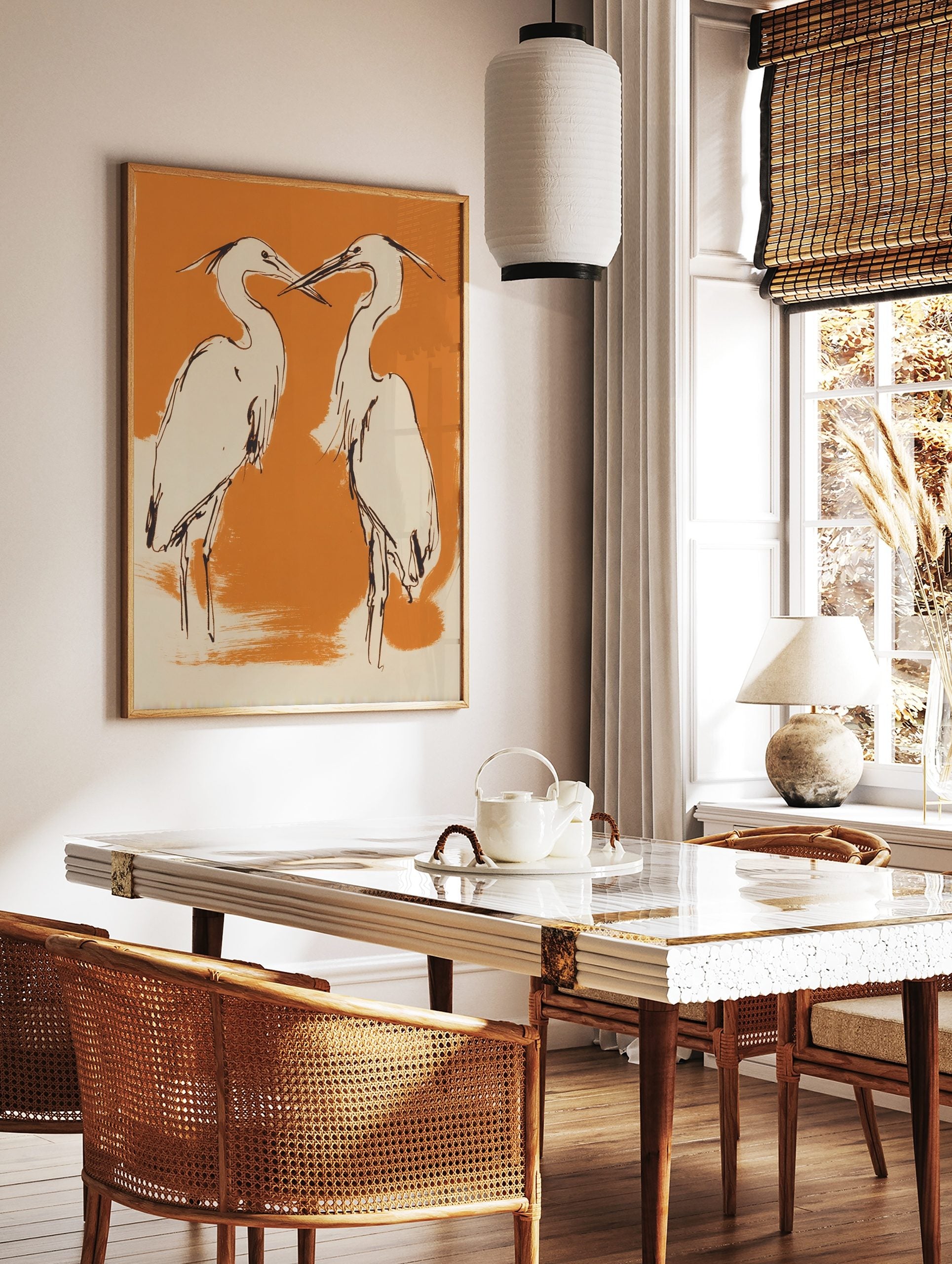 Illustrative art print of two herons with black outlines, cream bodies, on an orange background, in a styled room mockup