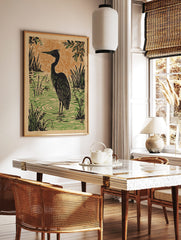 Illustrative black heron wading in green water with reeds, orange textured background in linocut, in a styled room mockup