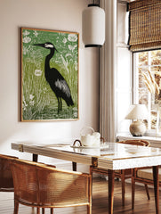 Illustrative green and black heron print standing in water amongst white botanical plants and reeds, in a styled room mockup