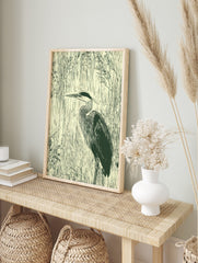 Illustrative dark green heron in profile against vertical cream reeds wall art print, in an alternate framed mockup