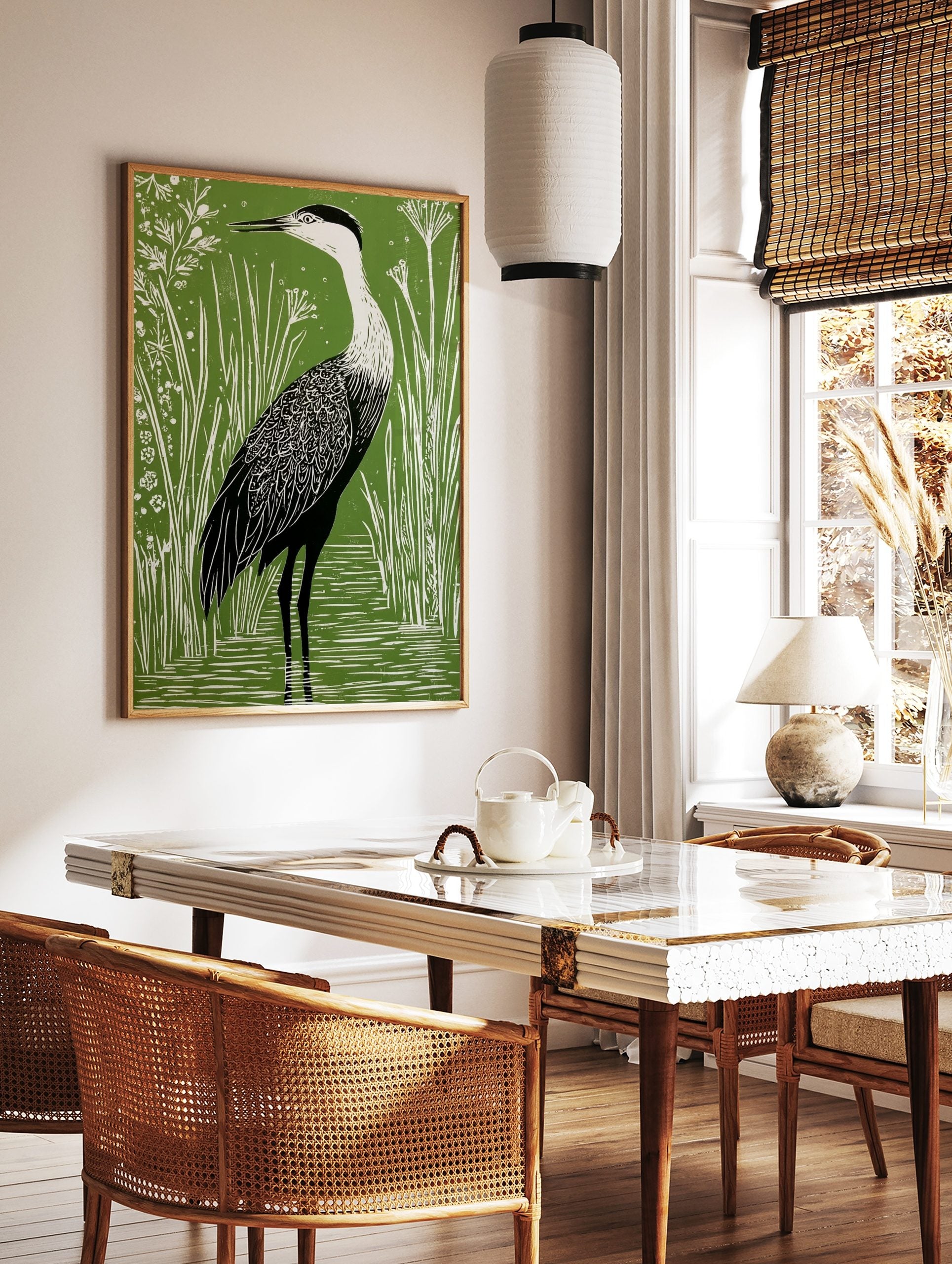 Green and white linocut style art print of a heron wading in water among tall reeds and small, in a styled room mockup