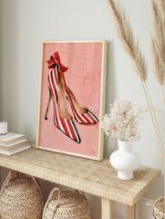 Illustrative print of red and white striped high heel shoes with a large red bow on a soft, in an alternate framed mockup