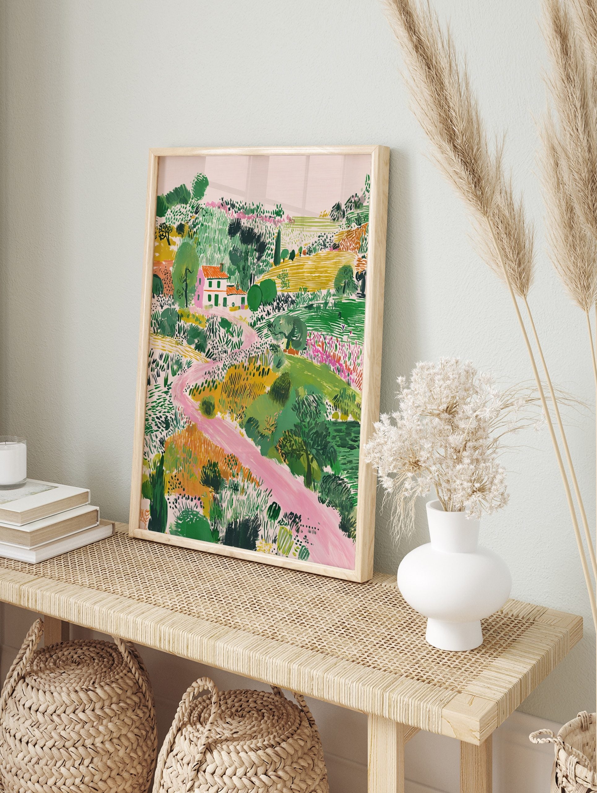 Illustrative landscape art print with a white house, orange roof, green fields, and a winding, in an alternate framed mockup