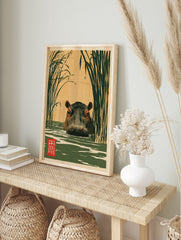Japanese-style illustration of a hippo in water surrounded by tall reeds with a red kanji, in an alternate framed mockup