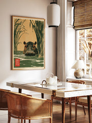 Japanese-style illustration of a hippo in water surrounded by tall reeds with a red kanji stamp, on, in a styled room mockup