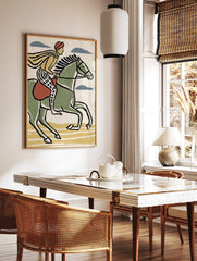 Illustrative print of a rider on a green horse with yellow cape and patterned trousers, moving right, in a styled room mockup