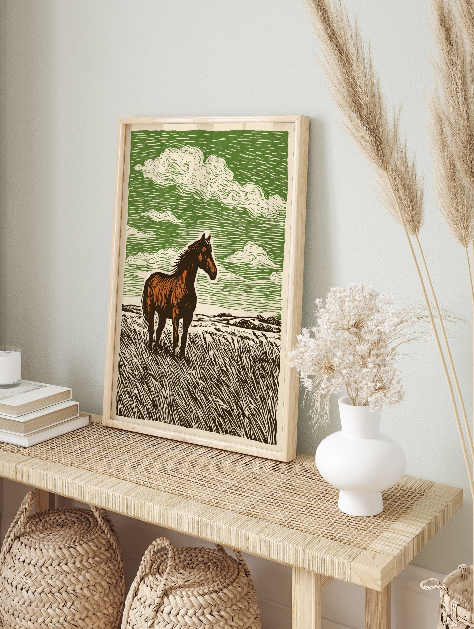 Brown horse standing in tall grass field with green sky and white clouds, linocut style art, in an alternate framed mockup