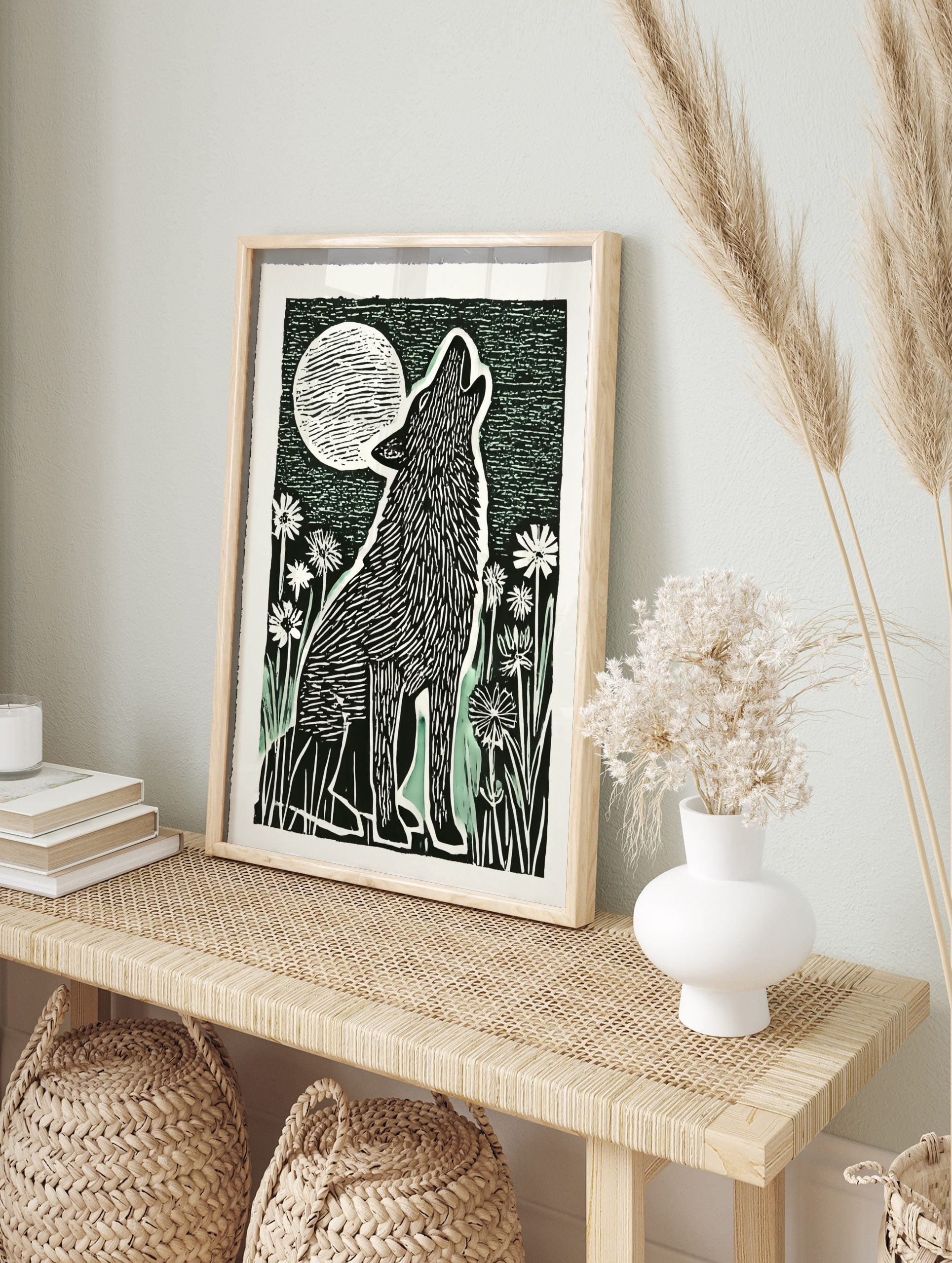 Linocut style art print of a howling wolf with a full moon and flowers in black, white, and, in an alternate framed mockup