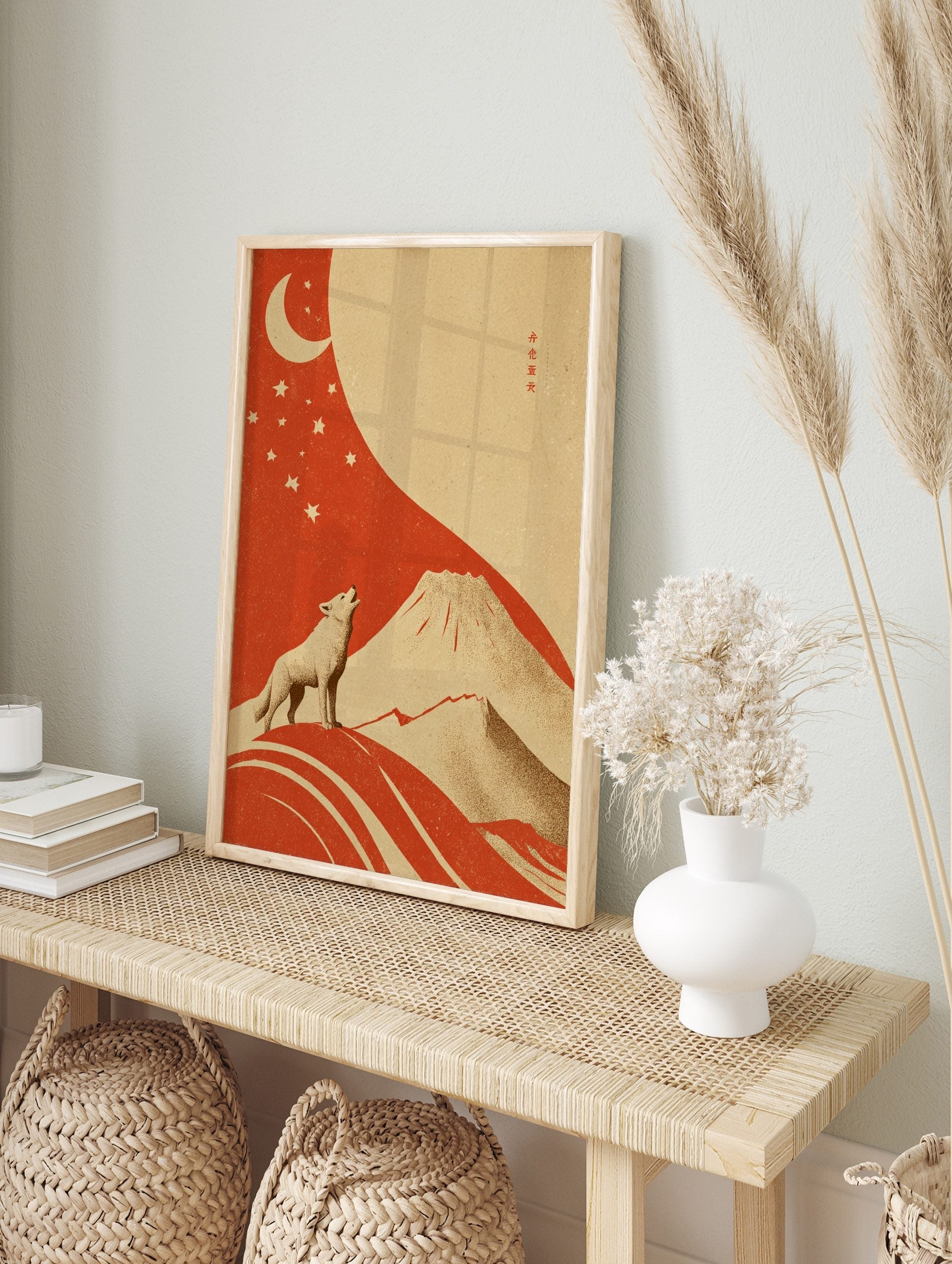 Illustrative art print of a howling wolf, crescent moon, stars, and Mount Fuji in red and, in an alternate framed mockup