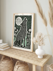 Illustrative black and white block print of a howling wolf under a large, striped full moon, in an alternate framed mockup