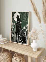 Black howling wolf linocut art print under a white full moon with white wildflowers on a, in an alternate framed mockup