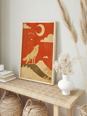 Illustrative print of a howling wolf on a hill, looking up at a crescent moon and stars, in an alternate framed mockup