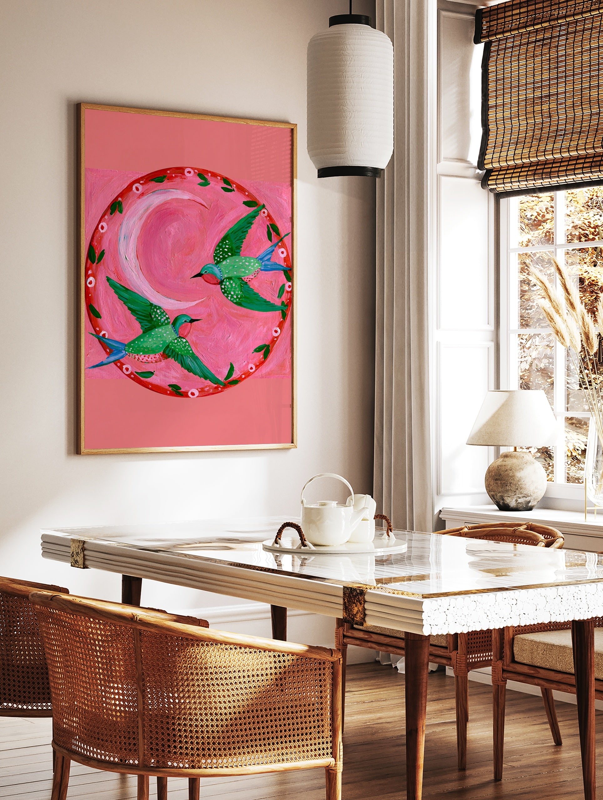 Two green hummingbirds with pink throats flying in a circle around a pink crescent moon on a pink, in a styled room mockup