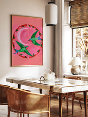 Two green hummingbirds with pink throats flying in a circle around a pink crescent moon on a pink, in a styled room mockup