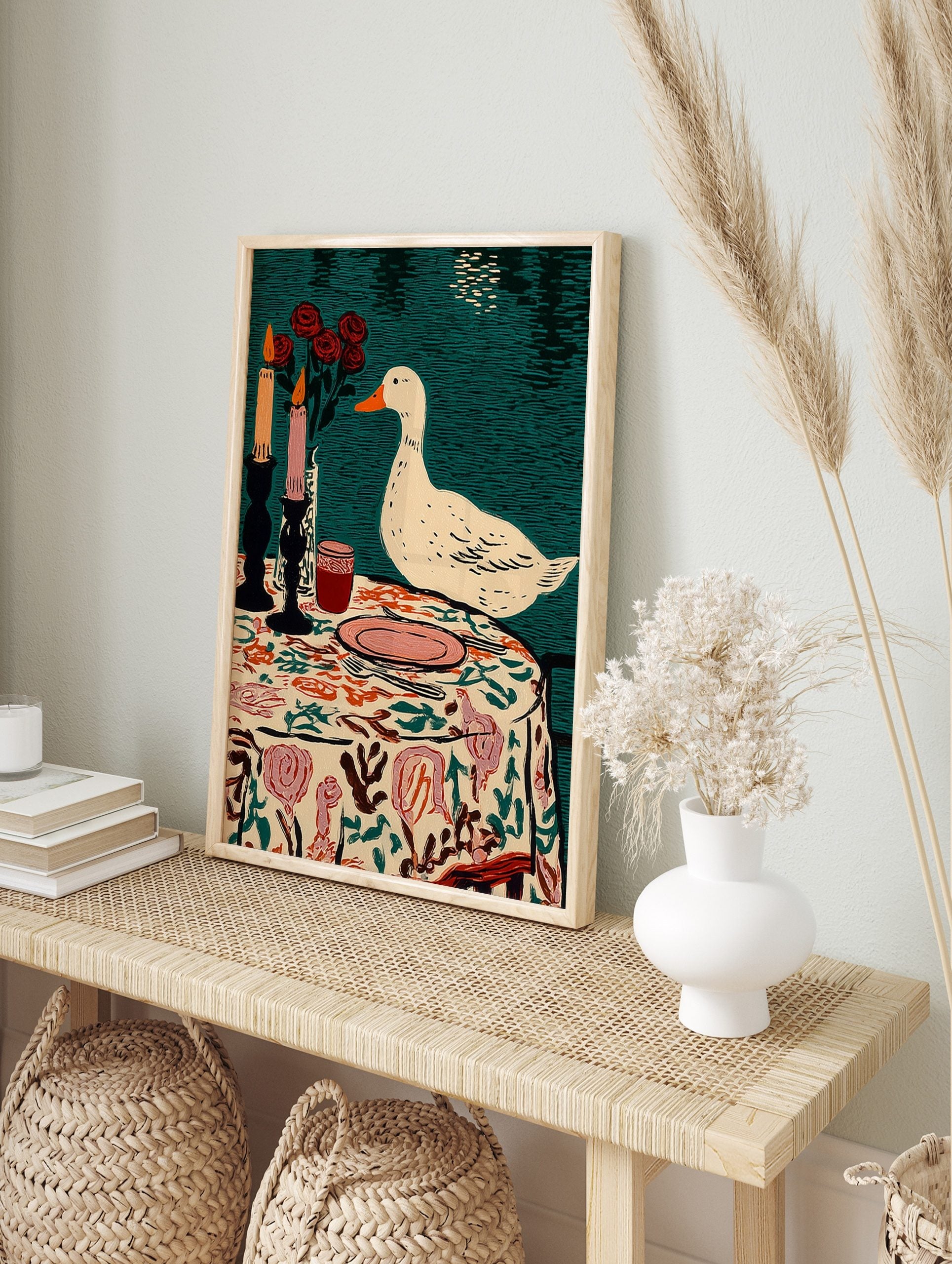 Illustrative print of a white duck observing a table setting with candles, red roses, and a, in an alternate framed mockup