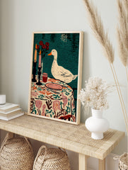 Illustrative print of a white duck observing a table setting with candles, red roses, and a, in an alternate framed mockup
