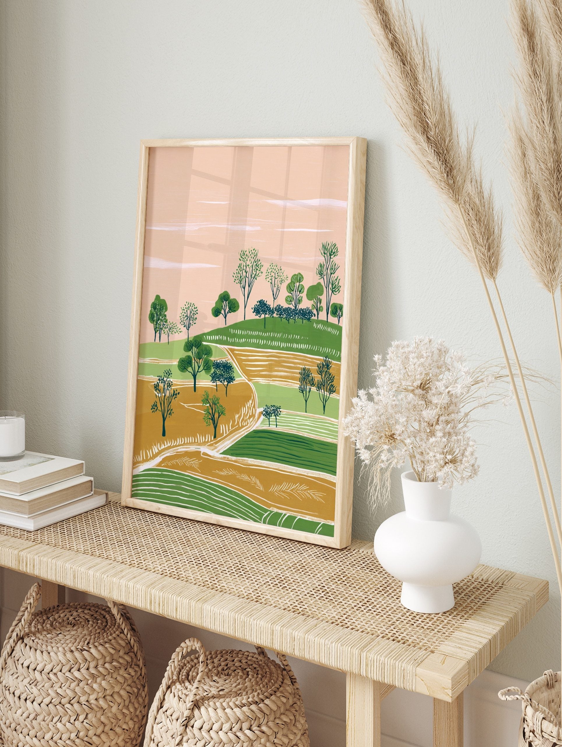 Illustrative landscape art print with green hills, gold fields, scattered trees, and a peach, in an alternate framed mockup