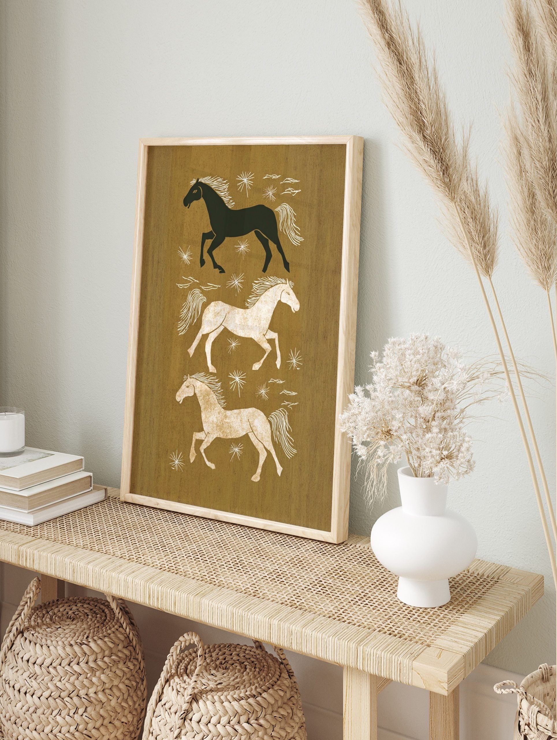 Three illustrative running horses in black, white, and tan on an earthy brown background with, in an alternate framed mockup