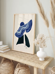 Illustrative wall art of a figure in a large, textured blue hat, with one hand holding the brim against a cream background. - Image 3