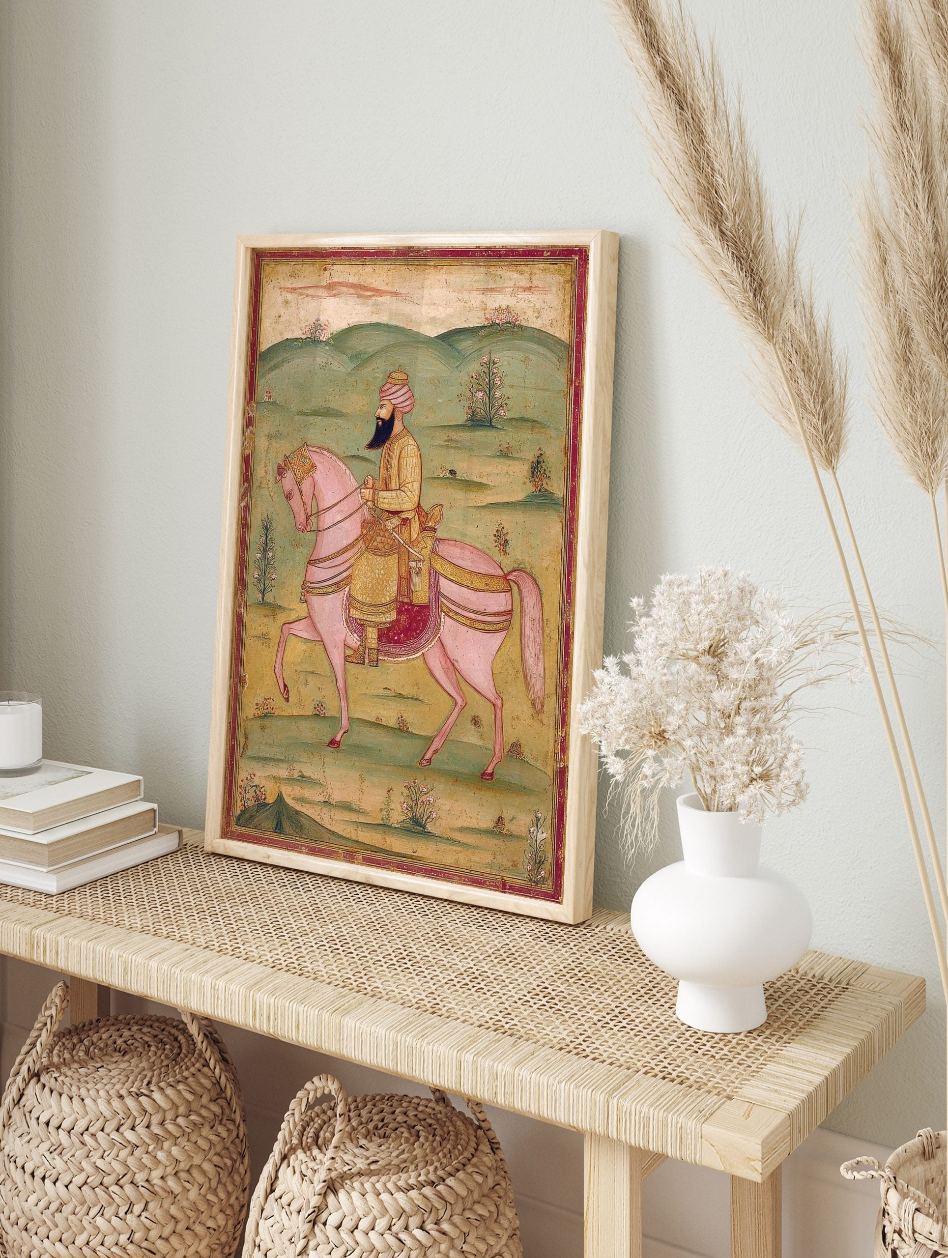 Indian miniature painting of a bearded man in a pink turban riding an ornate pink horse in a, in an alternate framed mockup