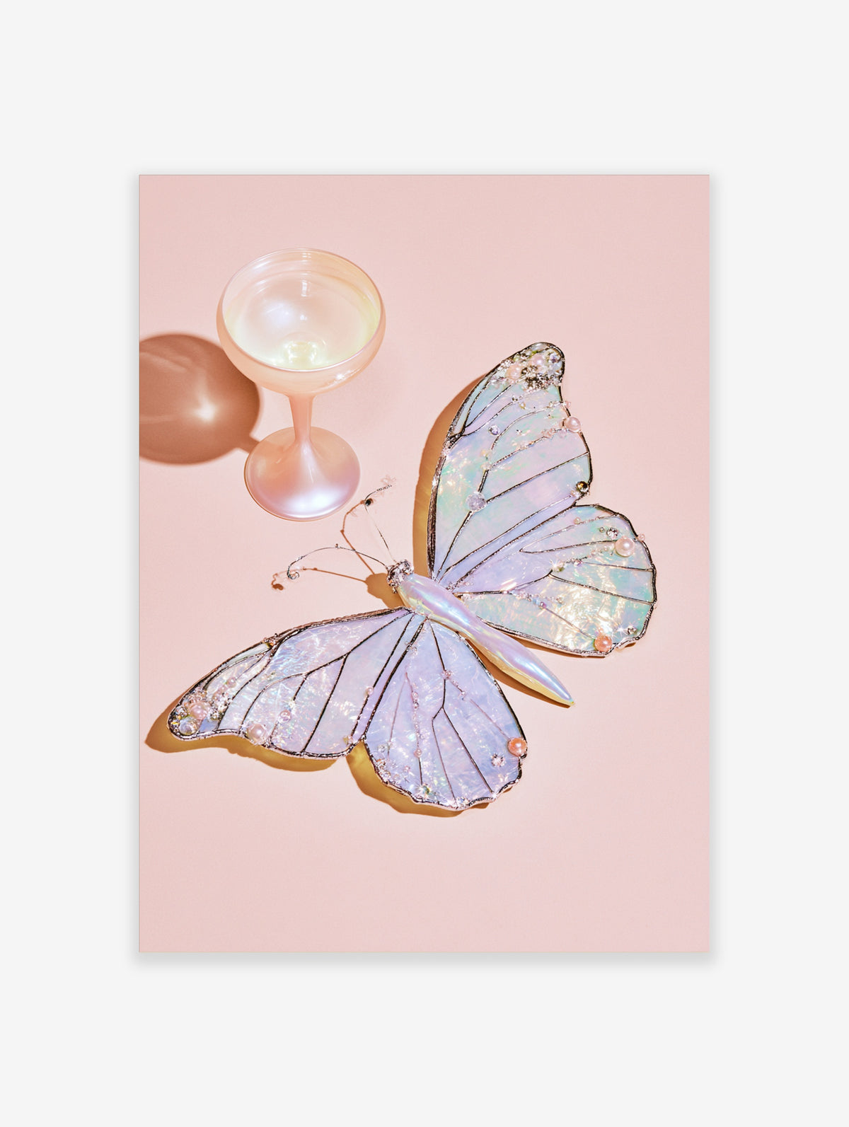 Iridescent butterfly art print with faux pearl details and a pink coupe glass on a pale pink background