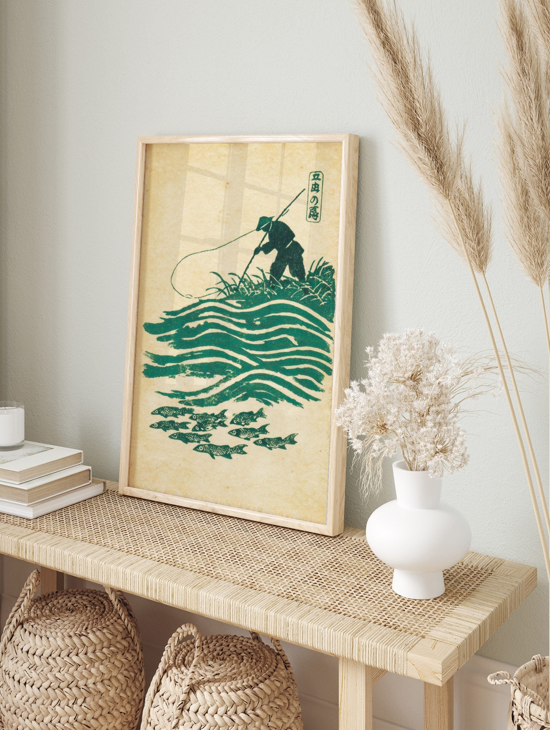 Japanese angler in conical hat fishing over green waves and school of fish in woodblock print, in an alternate framed mockup