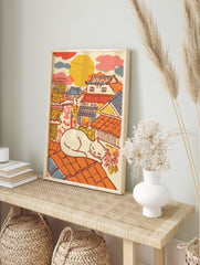 Illustrative Japanese Cat Art print of a white cat sleeping on an orange tiled roof overlooking a colorful traditional townscape. - Image 3