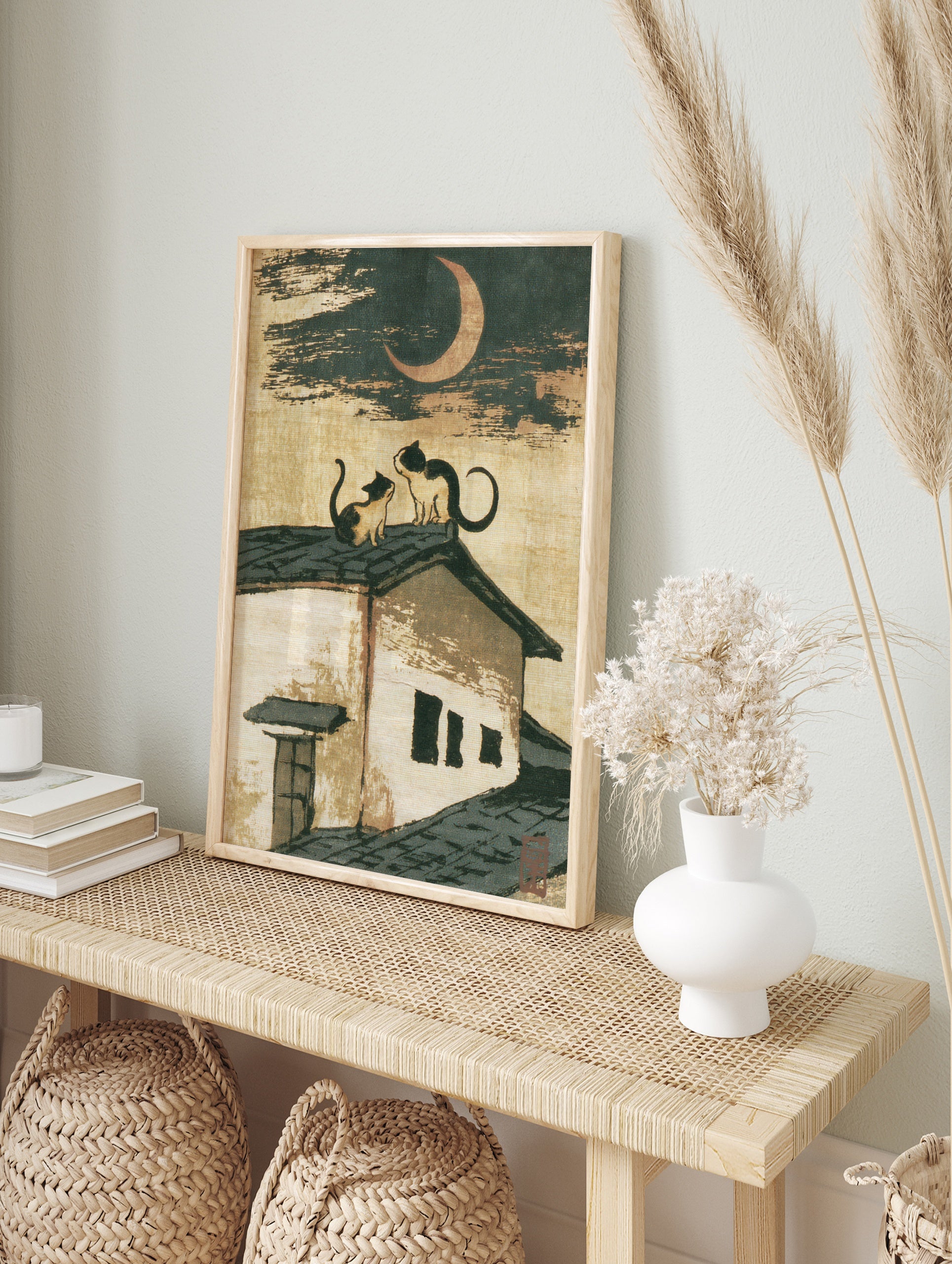 Japanese-style illustration of two cats sitting on a tiled roof beneath a crescent moon, in an alternate framed mockup