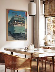 Japanese Ukiyo-e style art print of cats riding a teal tram with a distant mountain and blue sky, in a styled room mockup