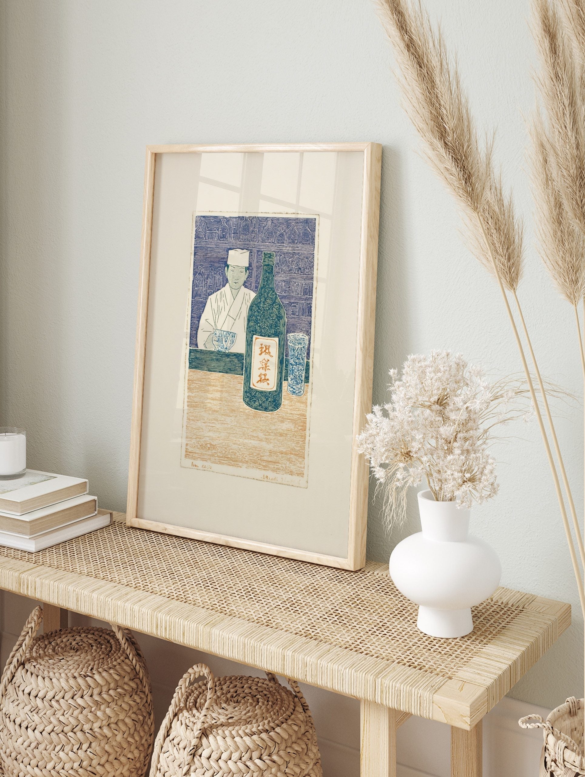 Japanese woodblock print of a chef with sake bottle and glass at a counter, in blue, cream, in an alternate framed mockup