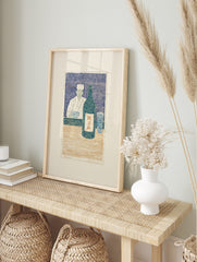 Japanese woodblock print of a chef with sake bottle and glass at a counter, in blue, cream, in an alternate framed mockup
