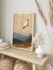 Japanese red-crowned crane flying over misty blue mountains and earthy grass landscape art, in an alternate framed mockup