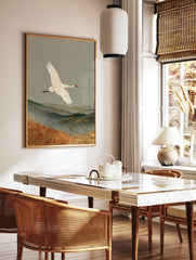 White crane flying over layered mountains and golden grasses, traditional Japanese style nature art, in a styled room mockup