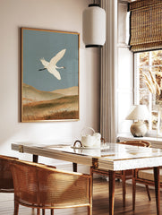 White crane in flight over earthy hills, Japanese-inspired nature wall art print, in a styled room mockup