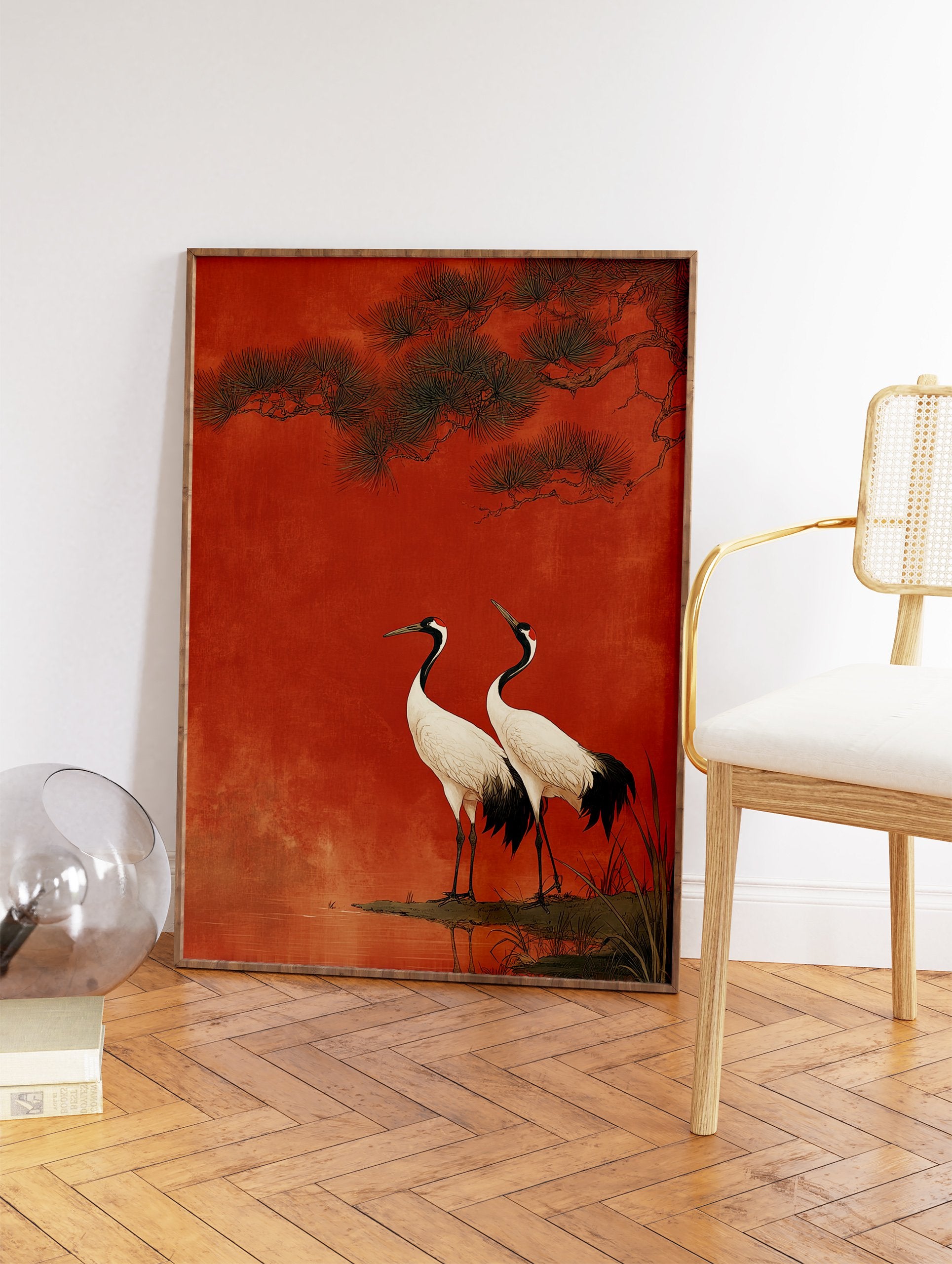 Two Japanese cranes with white bodies and black necks standing by water under pine branches against a textured red background. - Image 2