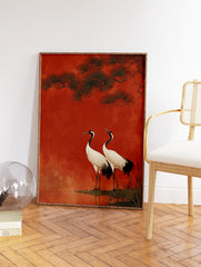 Two Japanese cranes with white bodies and black necks standing by water under pine branches against a textured red background. - Image 2