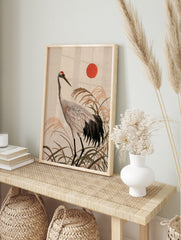 Japanese red-crowned crane illustration with tall reeds and a red sun, textured, in an alternate framed mockup