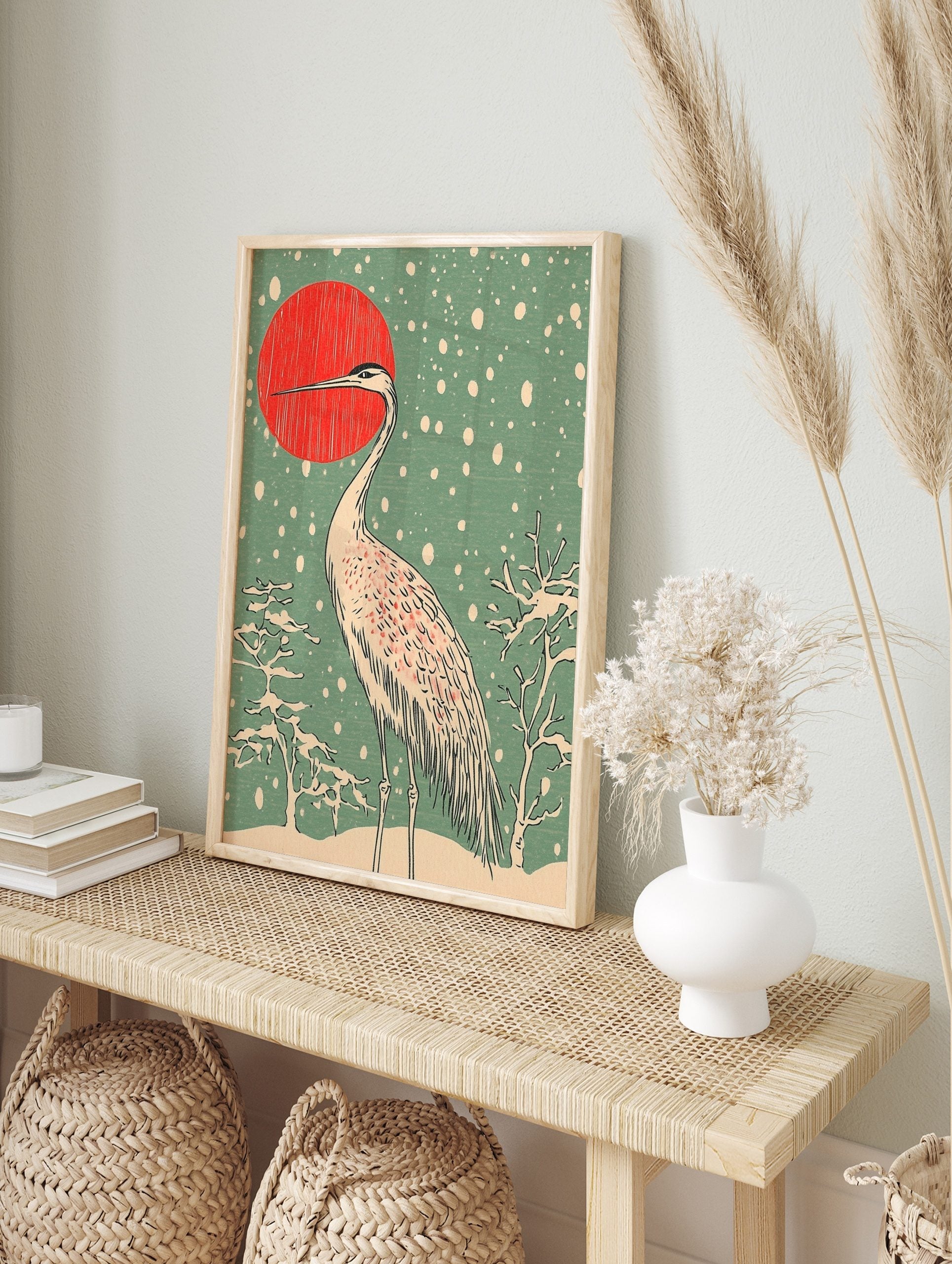Japanese crane standing in snow with red sun and snowflakes in woodblock print art style, in an alternate framed mockup