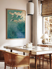 Japanese cranes in flight over water with green reeds and golden clouds, illustrative art print, in a styled room mockup