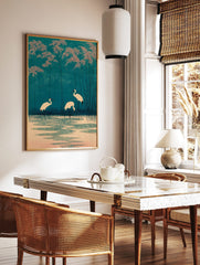 Japanese woodblock style print of three white cranes in teal water with pink foliage and tall reeds, in a styled room mockup