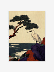 Japanese egret stands on a purple and red rocky cliff with a pine tree and dark blue sea