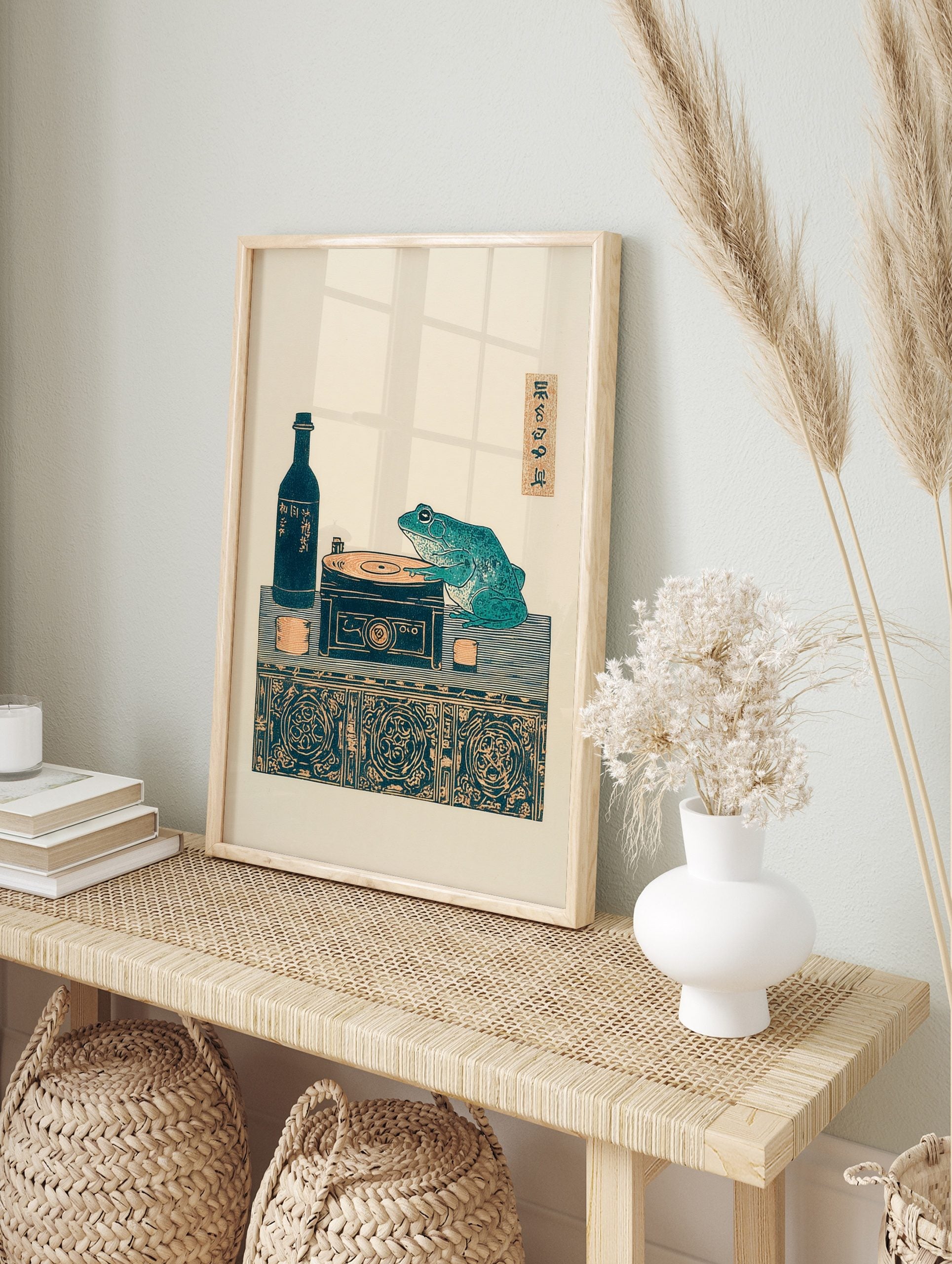Japanese Ukiyo-e style print of a teal frog on a record player with a sake bottle and cups on, in an alternate framed mockup