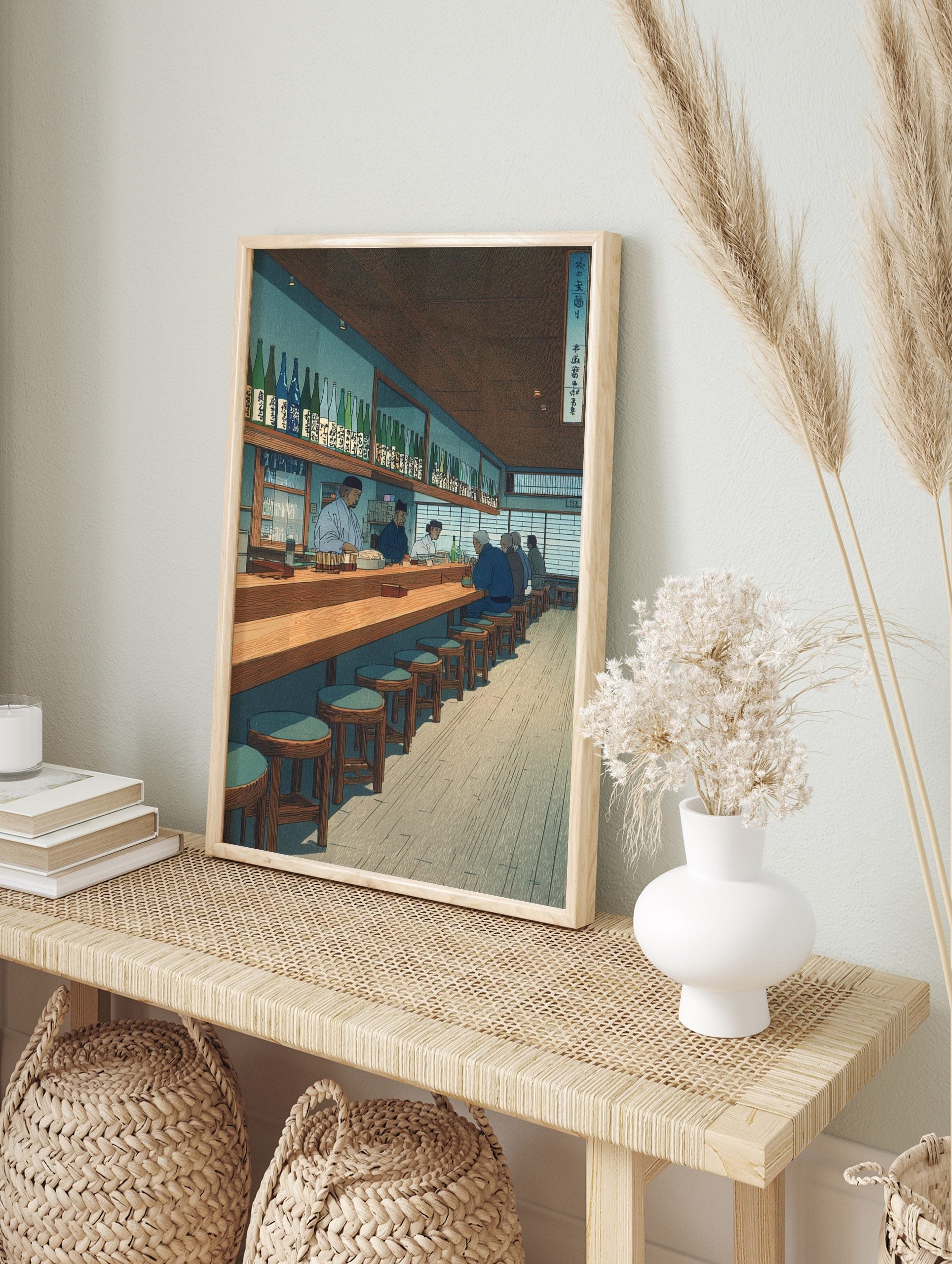 Japanese Izakaya interior art print with patrons and staff at a long wooden counter, shelves, in an alternate framed mockup