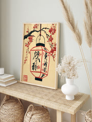 Japanese paper lantern hanging from cherry blossom branches with black kanji calligraphy on a, in an alternate framed mockup