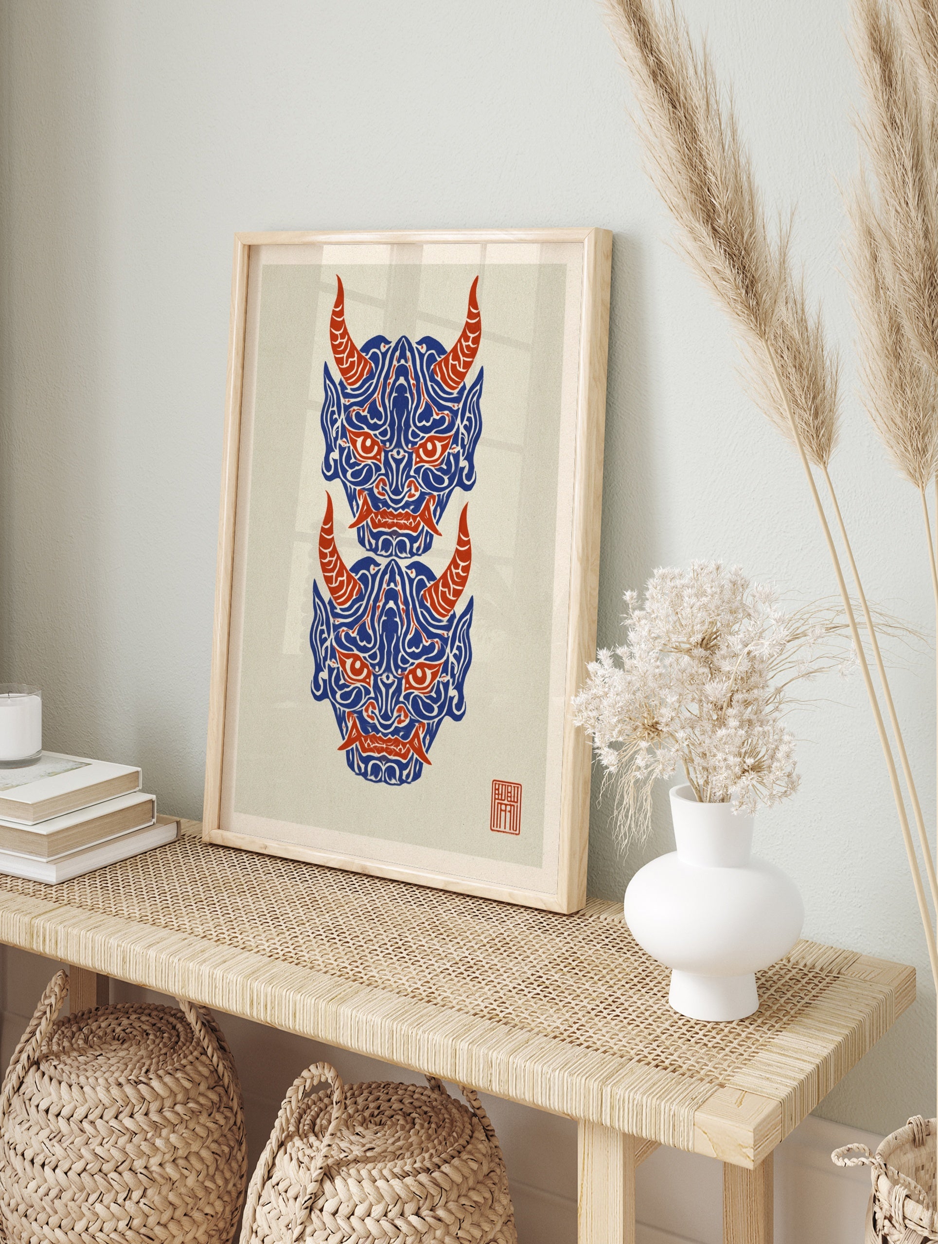 Japanese Oni mask wall art print with two stacked demon faces in blue and red on a cream, in an alternate framed mockup