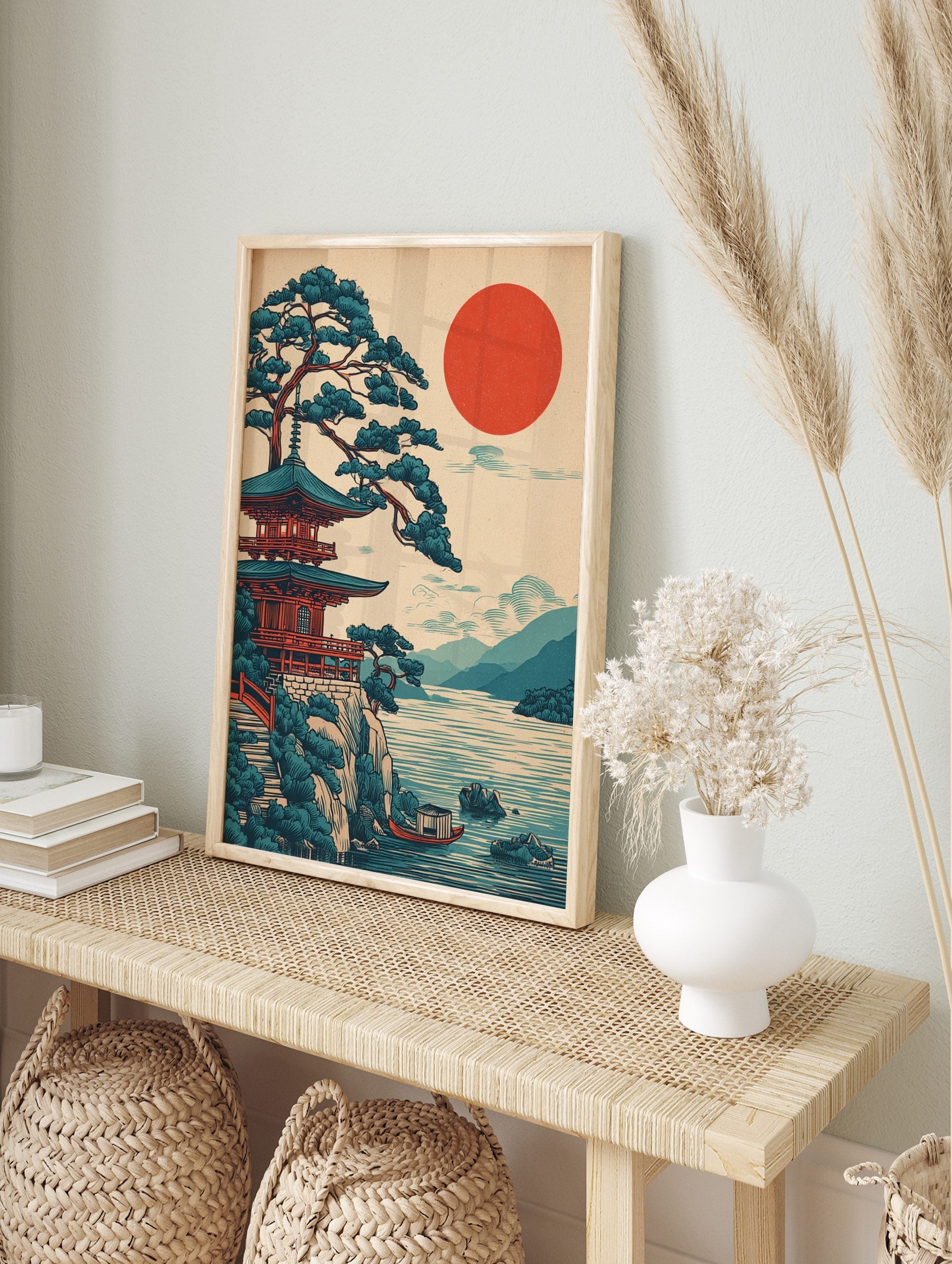 Japanese pagoda temple and pine tree on a cliff overlooking a lake with a red sun and, in an alternate framed mockup