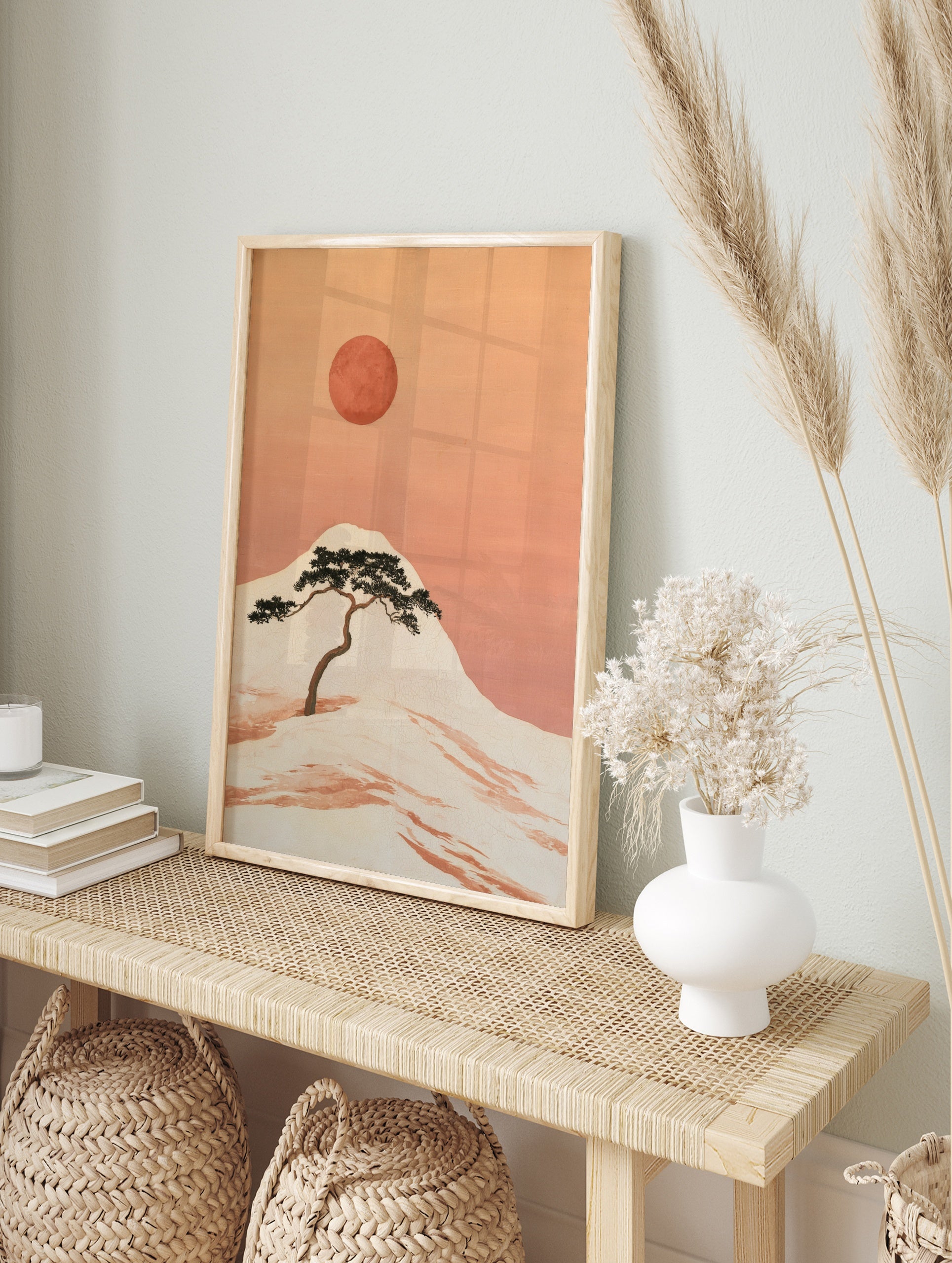 Japanese-style illustration of a pine tree on a hillside with a large red sun in an orange sky, in an alternate framed mockup