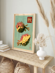 Japanese-style illustration of two orange and yellow spiny pufferfish with calligraphy on a, in an alternate framed mockup